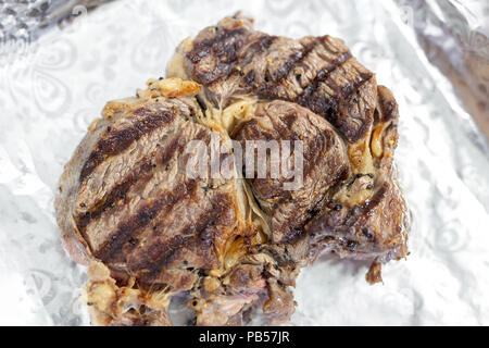 Close-up délicieux biftecks juteux bifteck sur le papier aluminium. . La viande de bœuf biologique assaisonné de poivre du moulin au four grill coocked après Banque D'Images