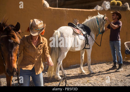 Couple dans la campagne préparer les chevaux pour aller en voyage de plein air et découvrir de nouvelles plces en excursion. ntaural de vie de plein air pour le bonheur et l'animal ther Banque D'Images