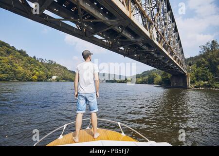 Jeune homme d'une excursion en bateau sur la Vltava et regarder sur pont de chemin de fer près de Prague, République tchèque. Banque D'Images