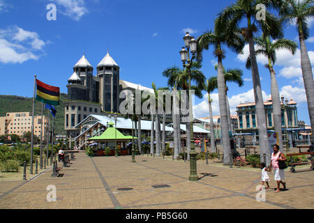 Pavillon de l'Ile Maurice au vent à la place principale bordée de palmiers devant le Caudan Waterfront à Port Louis, Ile Maurice Banque D'Images