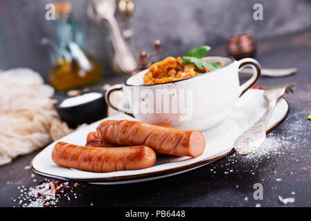 Les saucisses avec du chou frit dans un bol et sur une table Banque D'Images