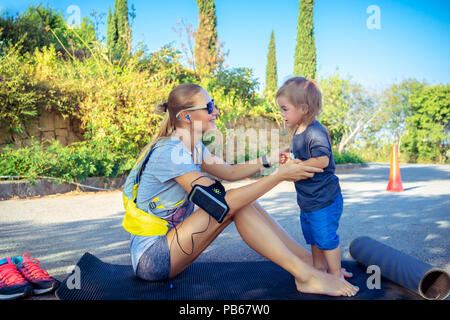 Belle mère sportive exercices faire dans le parc sur le tapis avec son petit fils, la famille bénéficie de sport ensemble, heureux de vie sain Banque D'Images