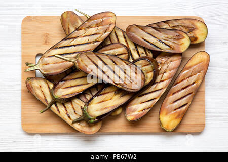 Vue de dessus, aubergines grillées sur conseil de bambou sur fond de bois blanc. Libre. Banque D'Images