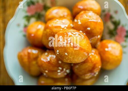 Boules de pâte frite sucrée avec du miel sur une plaque Banque D'Images