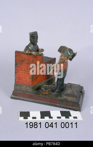 . Anglais : fonte banque mécanique. Montre un Italien mason travaillant sur un mur de briques avec un transporteur hod. Pour déposer une pièce de monnaie, il doit être placé dans le HOD. Frapper le levier permet de déplacer le hod avant pour permettre la pièce pour tomber dans un piège qui s'ouvre pour recevoir la médaille. Dans le même temps le maçon pose les deux mains, soulever une brique et truelle. Lorsque le levier est relâché, le piège de monnaie se ferme et tous les autres parties revenir à leur position antérieure. Fabriqué par l'entreprise de matériel vers 1887 Shepard. Titre : Mason et Hod Carrier pièce mécanique circa 1887 1004 Banque . Mason et Hod Carrier Banque D'Images