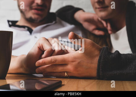 L'homme la main caresse une femme de main. Dans le contexte de l'homme heureux et la jeune fille sont visibles. Devant eux sur une table se trouve le téléphone. La phot Banque D'Images