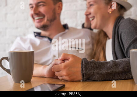 L'homme est titulaire d'une main dans la main. Dans le contexte de l'homme joyeux, souriant et la jeune fille sont visibles. Devant eux sur une table se trouve téléphone Banque D'Images