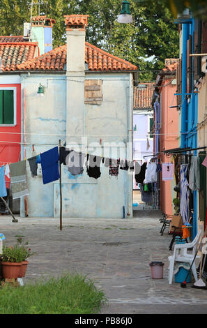 Vêtements blanchisserie tomber entre deux maisons dans un petit carré de Burano Banque D'Images