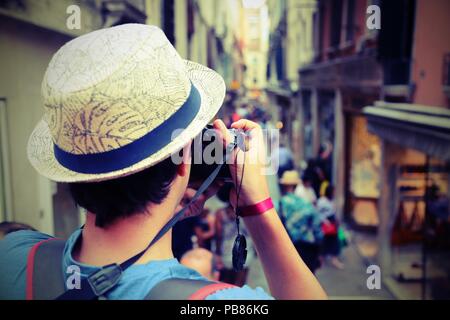 Jeune garçon avec appareil photo numérique prend de nombreuses photos d'une rue étroite appelée Calle en langue italienne à Venise en Italie avec effet vintage ancien Banque D'Images