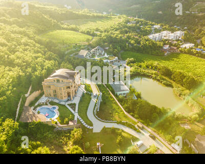 Vue de dessus de l'antenne du luxe chalet d'appartements avec piscine à proximité de bâtiments le lac de montagne sous le soleil de rêve Banque D'Images