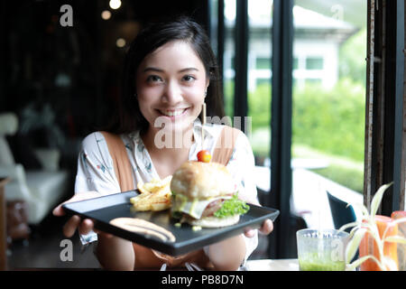 Asian women smiling et heureux et aimaient manger des hamburgers dans le café et restaurant sur le temps de vous détendre Banque D'Images