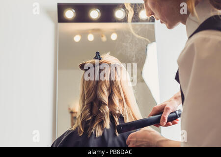 Coiffure coiffure pour un client avec un fer à friser en instituts de beauté Banque D'Images