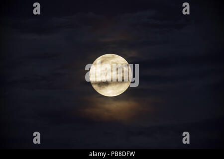 Pleine lune lumineuse contre nuages sombres Banque D'Images