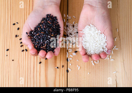 Riz Noir et blanc dans les mains. Studio Photo Banque D'Images