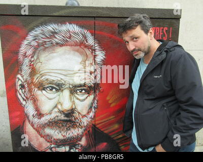 France, Paris. 11 juillet, 2018. Christian Guemy, artiste de rue, et connu sous le pseudonyme de C215, est debout à côté d'un portrait de Victor Hugo. L'œuvre d'art fait partie de l'exposition 'Illustres', qui sera montré dans le 8.10.2018 jusqu'au Panthéon de Paris et ses environs. Credit : Sabine Glaubitz/dpa/Alamy Live News Banque D'Images