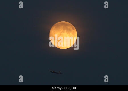 Le nord de Londres. Londres. UK 26 Juillet 2018 - Un avion de British Airways au-dessous de la Lune de sang dans le nord de Londres, comme la plus longue éclipse lunaire du siècle, fixée pour le vendredi 27 juillet 2018, a déjà commencé en tournant le corps céleste une profonde couleur écarlate. La Lune de sang sera le premier britannique de chance de voir un grand eclipse en 2018, et selon la NASA's Moon experts au Centre spatial Goddard, l'éclipse durera environ une heure et 43 minutes. Credit : Dinendra Haria/Alamy Live News Banque D'Images