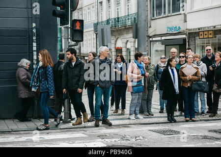 Portugal, Porto, 05 mai 2018 : une foule de gens se tient sur un feu rouge et attendre le feu vert à leur tour pour traverser la rue. Banque D'Images