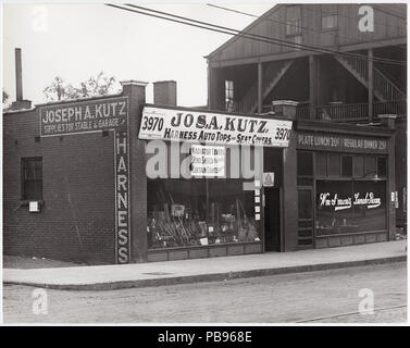 . Anglais : horizontale, noir et blanc photographie montrant Joseph A. Kutz's store au 3970 Chouteau. Le bâtiment en brique d'un étage dispose d'une grande fenêtre avant l'affichage des balais, des râteaux ou des fourches, de lampes, et d'autres équipements ont besoin d'une voiture ou stable. L'avant de signer le texte dit : "Jos. A. Kutz. Faisceau / Auto-tops et des housses de siège. Couvre Radiateur / / / rideaux pare-brise feux Rideau remplacé.' un signe peint sur le côté de l'édifice se lit comme suit : "Joseph A. Kutz / Fournitures pour stable et Garage / faisceau." La publicité des signes d'affaires voisins lire : 'HM S'mon's Lunch / Déjeuner Chambre plaque 20 cents / R Banque D'Images