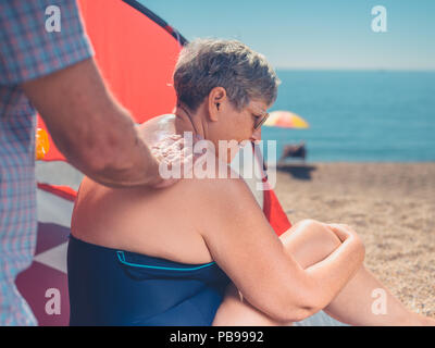 A senior man est l'application de la crème solaire à sa femme est de retour Banque D'Images