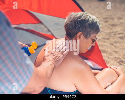 A senior man est l'application de la crème solaire à sa femme est de retour Banque D'Images