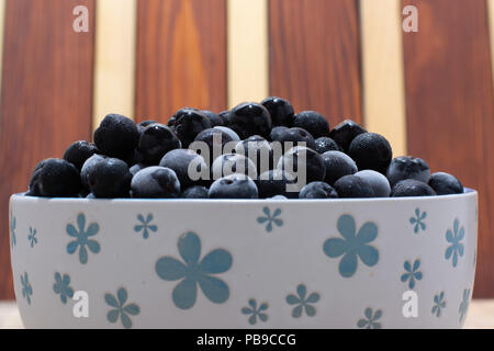 Bol blanc avec plein de petits fruits congelés aronia table rustique en bois Banque D'Images