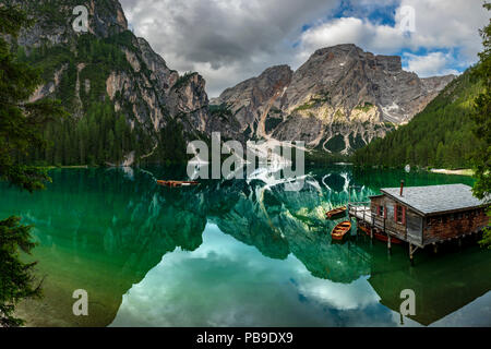 Lac de montagne verte avec des bateaux et d'un hangar à bateaux, Seekogel point culminant en l'arrière, de l'eau reflet, lac Prags, Dolomites, Italie Banque D'Images