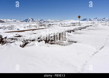 Route couverte de neige à travers désert d'Atacama avec road sign in front of Andes, Altiplano, Bolivie Banque D'Images