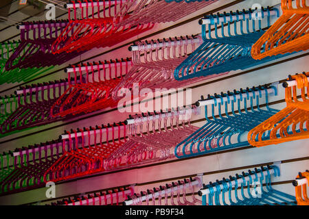 Cintre multicolore plastique arrière-plan. Orange, bleu, rouge, rose et violet des cintres sur un magasin pour la vente. Pas de personnes. Banque D'Images