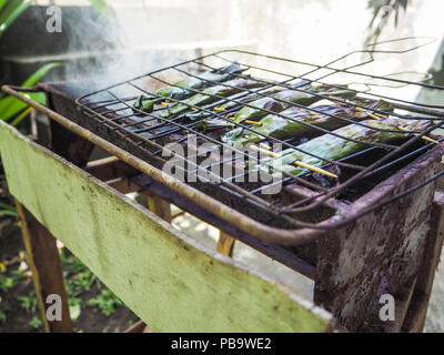 Les poissons dans des feuilles de bananier ( appelé Pepes Ikan) grillées sur un barbecue, Ubud, Bali Banque D'Images