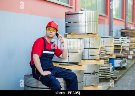 Worker talking sur son téléphone portable à l'extérieur de l'usine Banque D'Images