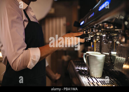 Cropped shot de barista à l'aide d'une cafetière pour préparer une tasse de café. Faire un travailleur féminin cafe café. Banque D'Images