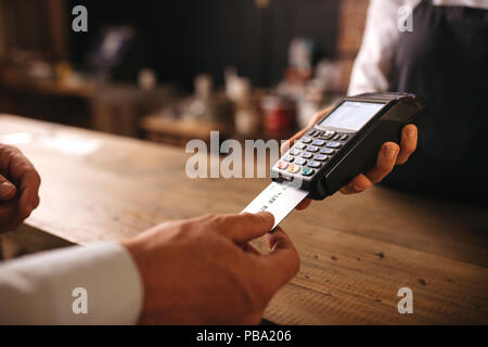 L'insertion de sa carte de crédit du client dans la machine à café au paiement. Le client paie pour sa commande avec une carte de crédit dans un café, avec barman hol Banque D'Images