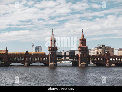 Vieux pont rouge avec deux tours, Oberbaum bridge, sur la rivière Spree à Berlin avec un tram train jaune aller plus de. Banque D'Images