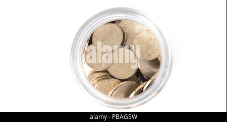 Close up pièces dans un bocal en verre sur le tableau blanc. Coins éparpillés. Isolé sur fond blanc. Banque D'Images
