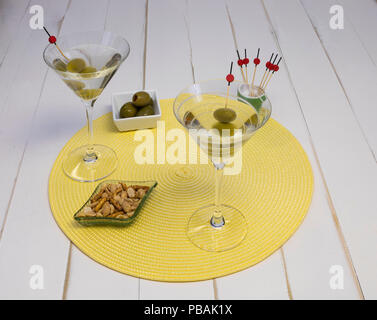 Deux verres de vodka martini avec des olives et des en-cas sur un napperon, vue de face. Banque D'Images