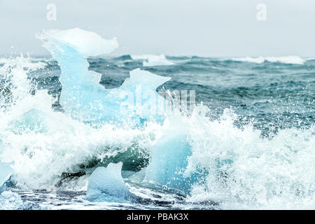 Vagues se brisant sur la plage du Diamant Jokulsarlon glacial glace Glacier en Islande contre les icebergs, les projections d'eau sur la rive de l'océan Atlantique au cours de pleuvoir, r Banque D'Images