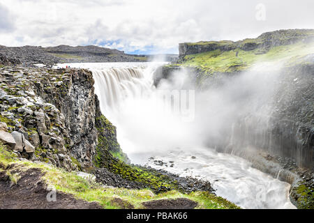 Cascade de Dettifoss Islande, Islande, plus grand volume en Europe, de l'eau gris gris, falaise rocheuse, les roches, le sol, l'herbe verte, l'eau qui coule, la pulvérisation de brouillard Banque D'Images