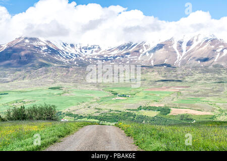 Vue sur la montagne près de Akureyri Sulur avec ciel bleu, nuages, saleté de gravier, pâturage, ferme, glacier, neige Banque D'Images