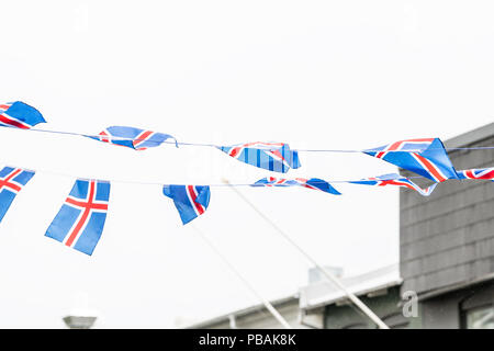 Isolés contre nuageux, couvert, ciel blanc de nombreux drapeaux nationaux islandais sur corde à Reykjavik le rue avec des bâtiments, l'eau de pluie gouttes de pluie Banque D'Images