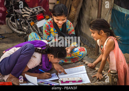 AHMEDABAD, INDE - Le 10 décembre 2017 : l'école de filles non identifié à l'origine ethnique Indien assis sur lit bébé fait ses devoirs avec les livres et les cahiers d'exercices. Banque D'Images