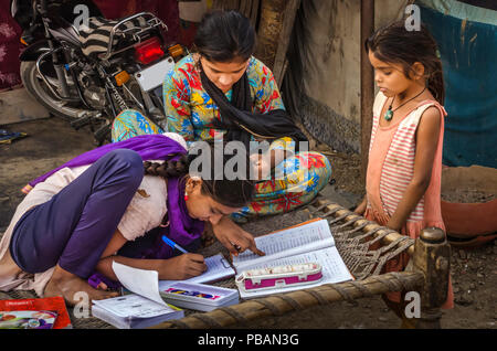 AHMEDABAD, INDE - Le 10 décembre 2017 : l'école de filles non identifié à l'origine ethnique Indien assis sur lit bébé fait ses devoirs avec les livres et les cahiers d'exercices. Banque D'Images