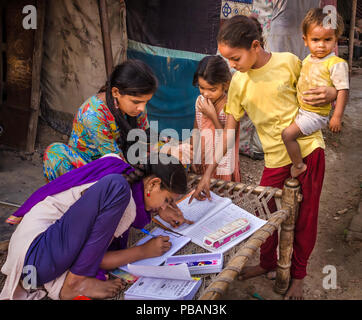 AHMEDABAD, INDE - Le 10 décembre 2017 : l'école de filles non identifié à l'origine ethnique Indien assis sur lit bébé fait ses devoirs avec les livres et les cahiers d'exercices. Banque D'Images