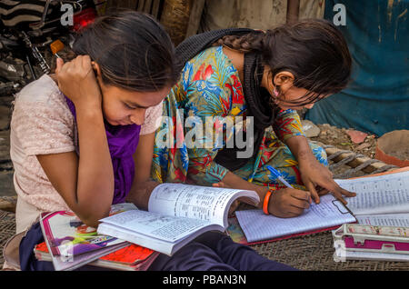 AHMEDABAD, INDE - Le 10 décembre 2017 : l'école de filles non identifié à l'origine ethnique Indien assis sur lit bébé fait ses devoirs avec les livres et les cahiers d'exercices. Banque D'Images