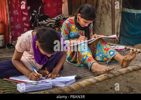 AHMEDABAD, INDE - Le 10 décembre 2017 : l'école de filles non identifié à l'origine ethnique Indien assis sur lit bébé fait ses devoirs avec les livres et les cahiers d'exercices. Banque D'Images