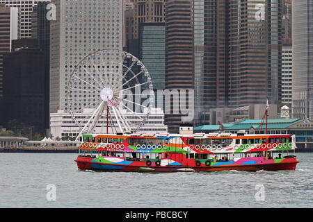 Le Star Ferry à Hong Kong transporte des passagers sur le port de Victoria avec flou de gratte-ciel dans le fond de la côte de l'île. Banque D'Images