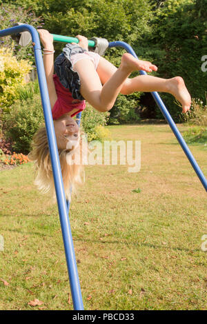 Trois ans, fille, faisant de l'acrobatie sur appareil de gymnastique dans le jardin arrière pour jouer, au Royaume-Uni. Banque D'Images