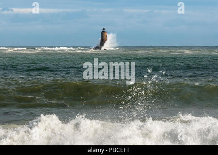 Marée haute unique provoque des vagues énormes de rompre le long de la côte et autour d'un phare en pierre dans la distance dans le Maine. Banque D'Images