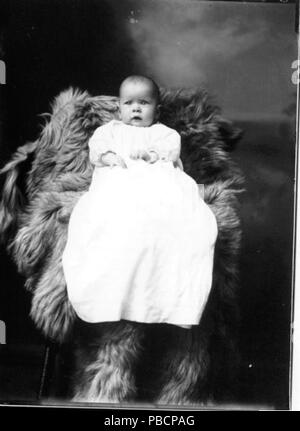1219 Portrait photo de bébé en longue robe assis sur des peaux de fourrure (1912) 3191705894 Banque D'Images