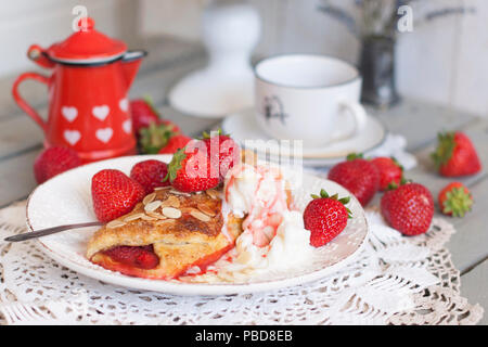 Des pâtisseries sucrées pour le petit-déjeuner. Avec le remplissage de fraises et de la crème glacée. Le café du matin. Pot à lait rouge. laitier. Une tasse de thé. petit déjeuner en famille. Photo en couleurs blanc Banque D'Images