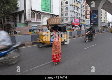 Indian woman carrying charge sur head crossing road à Hyderabad, Inde Banque D'Images